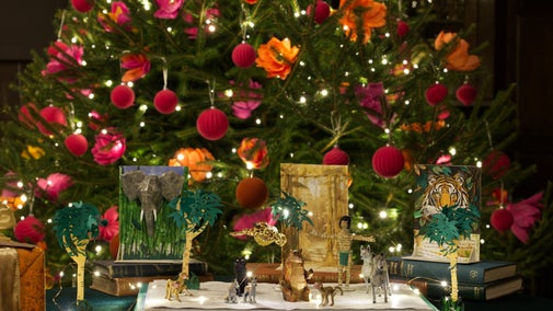 Historic room decorated for Christmas with a glowing tree, colourful ornaments